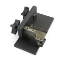 Angled view of AK-Builder black anodized rivet drilling fixture clamping an unfinished AK front trunnion.
