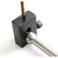 Close-up of AK-Builder black heat-treated steel gas piston drilling jig holding piston and TiN coated drill bit.